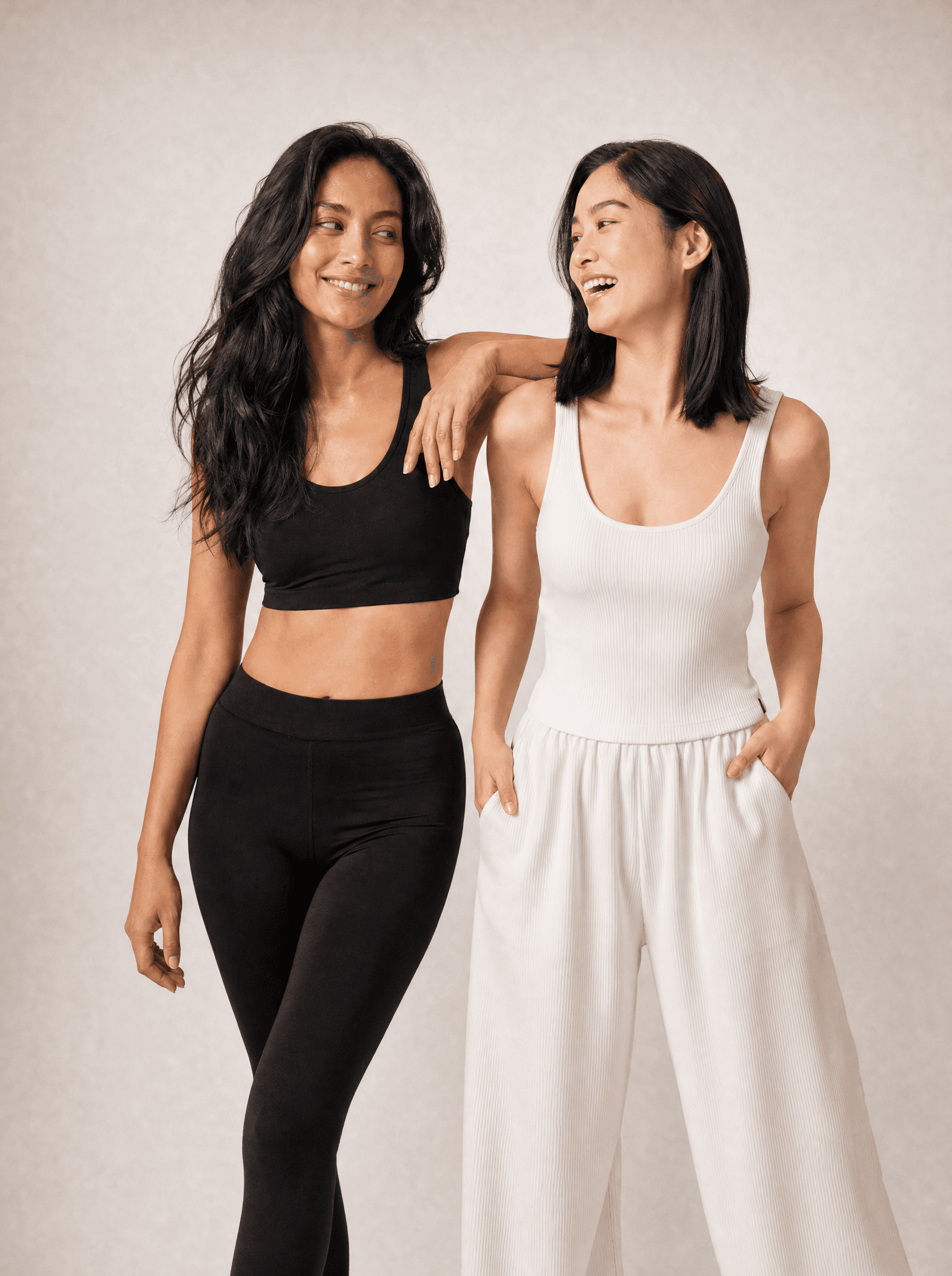Two women laughing together in a warm grey studio
